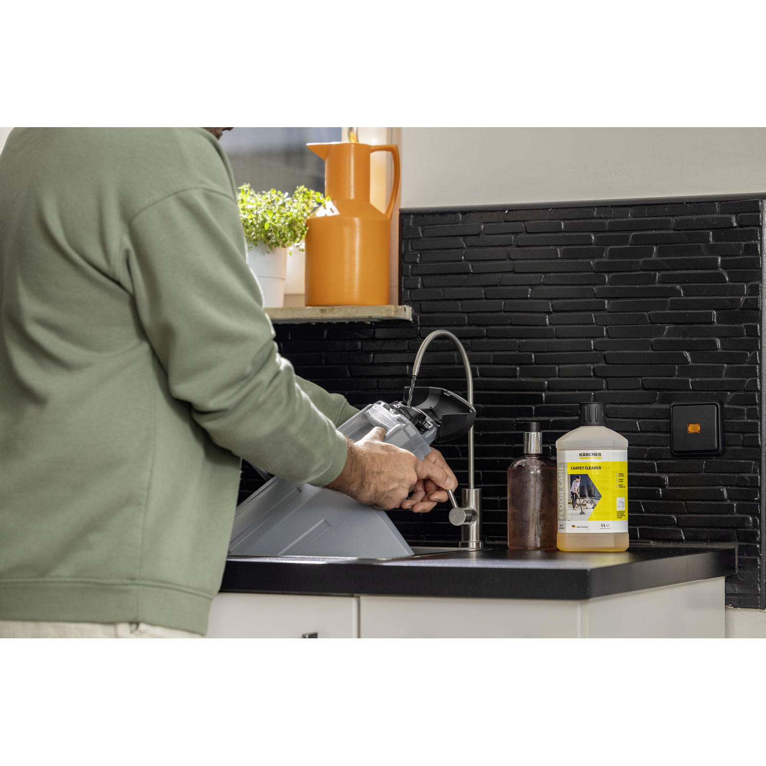Homme nettoyant un filtre d'aspirateur dans un évier avec des produits de nettoyage.