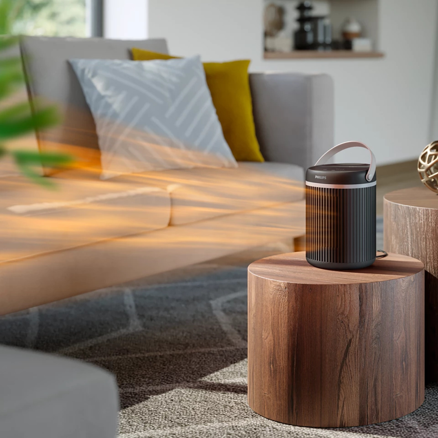 A dark cylindrical space heater sitting on a wooden stool in a living room.