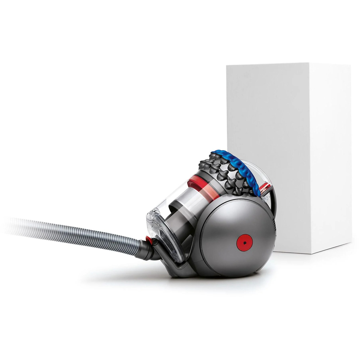 Gray, red, and blue vacuum cleaner with a hose, next to a white box on a white background.