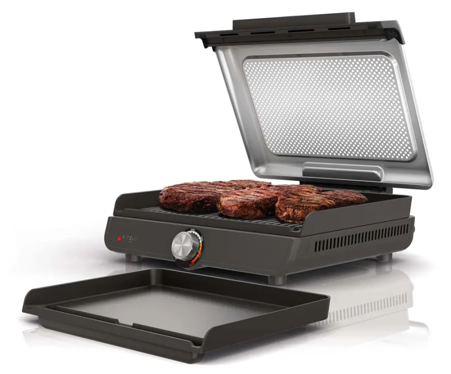 Egy zárt grill steakekkel a rácson és egy leválasztott tálcával.
