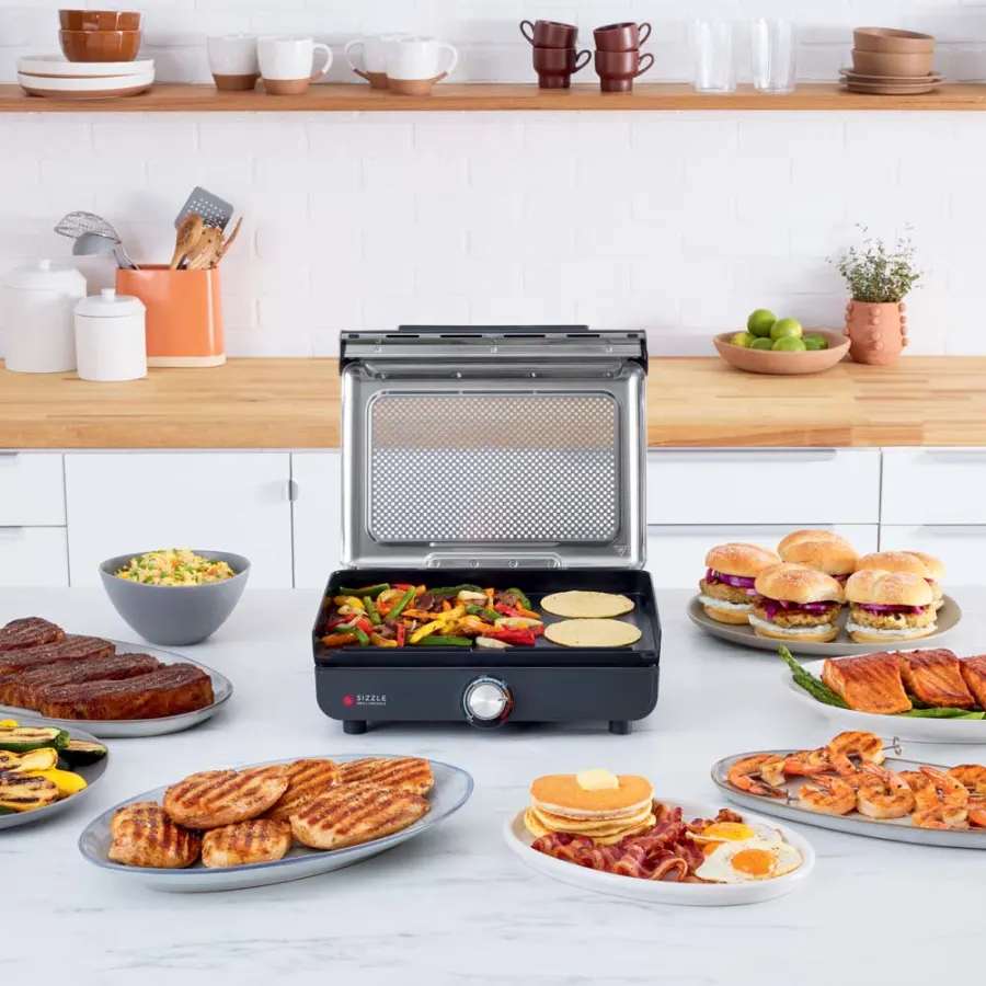 Egy grill különféle sült ételekkel, például steakekkel, hamburgerekkel és palacsintákkal.