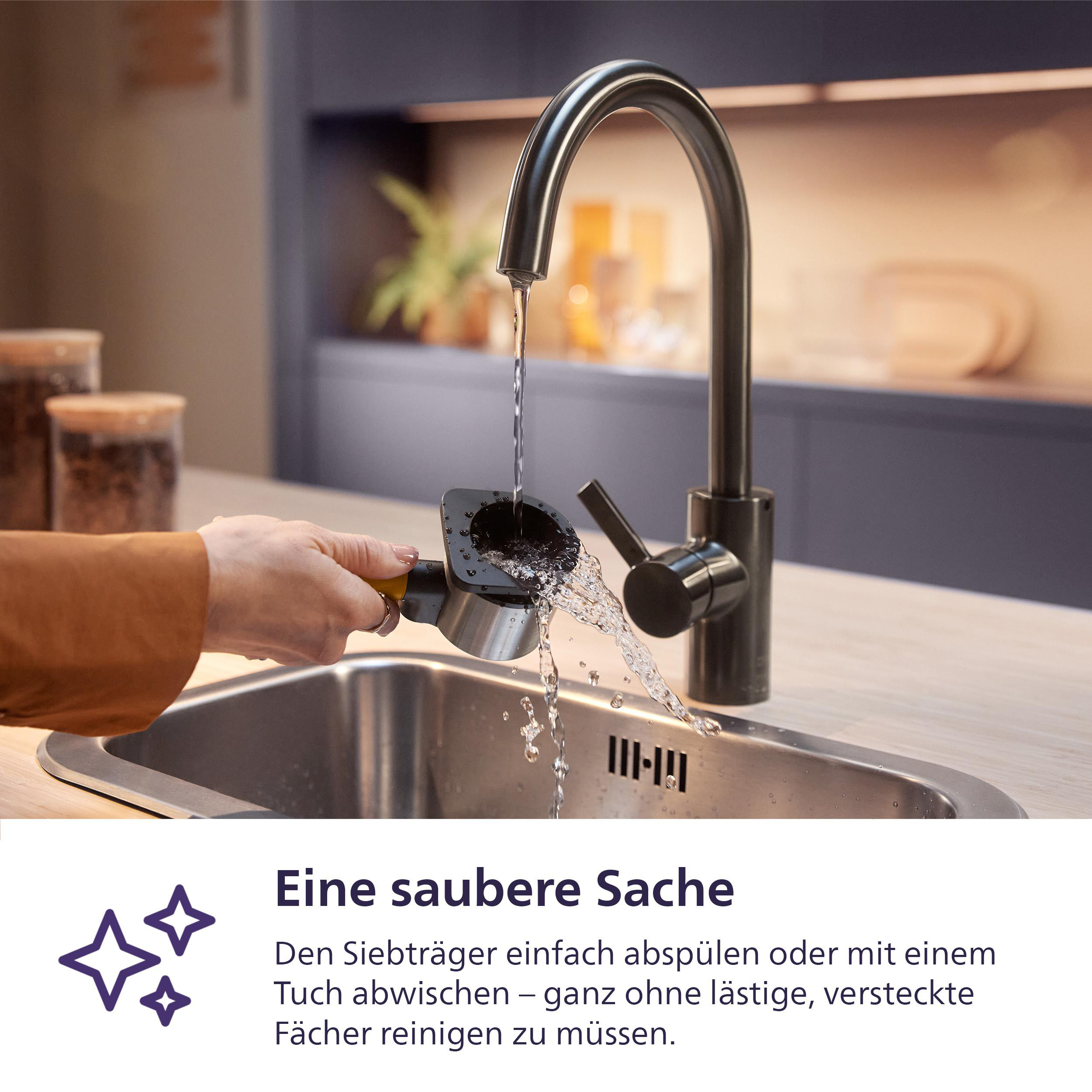 Ein Wasserhahn und ein Waschbecken, wobei Wasser aus dem Wasserhahn in einen schwarzen Espressomaschinenteil läuft.