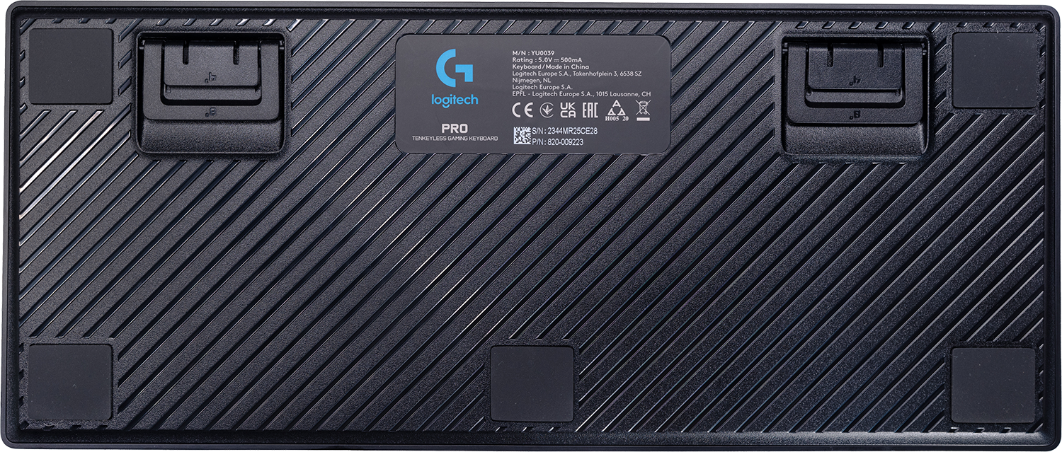 Egy fekete Logitech Pro billentyűzet alja. Több gumi láb, egy termékcímke és egy sorozatszám látható.