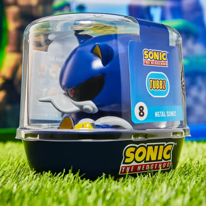 Egy Metal Sonic figura egy műanyag tokban, zöld füvön ülve. A háttér elmosódott.