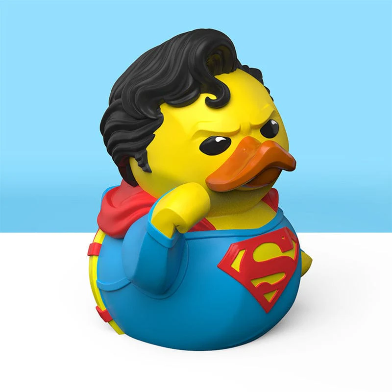 Egy Superman kacsa játék sárga testtel, fekete hajjal és Superman logóval a mellkasán.