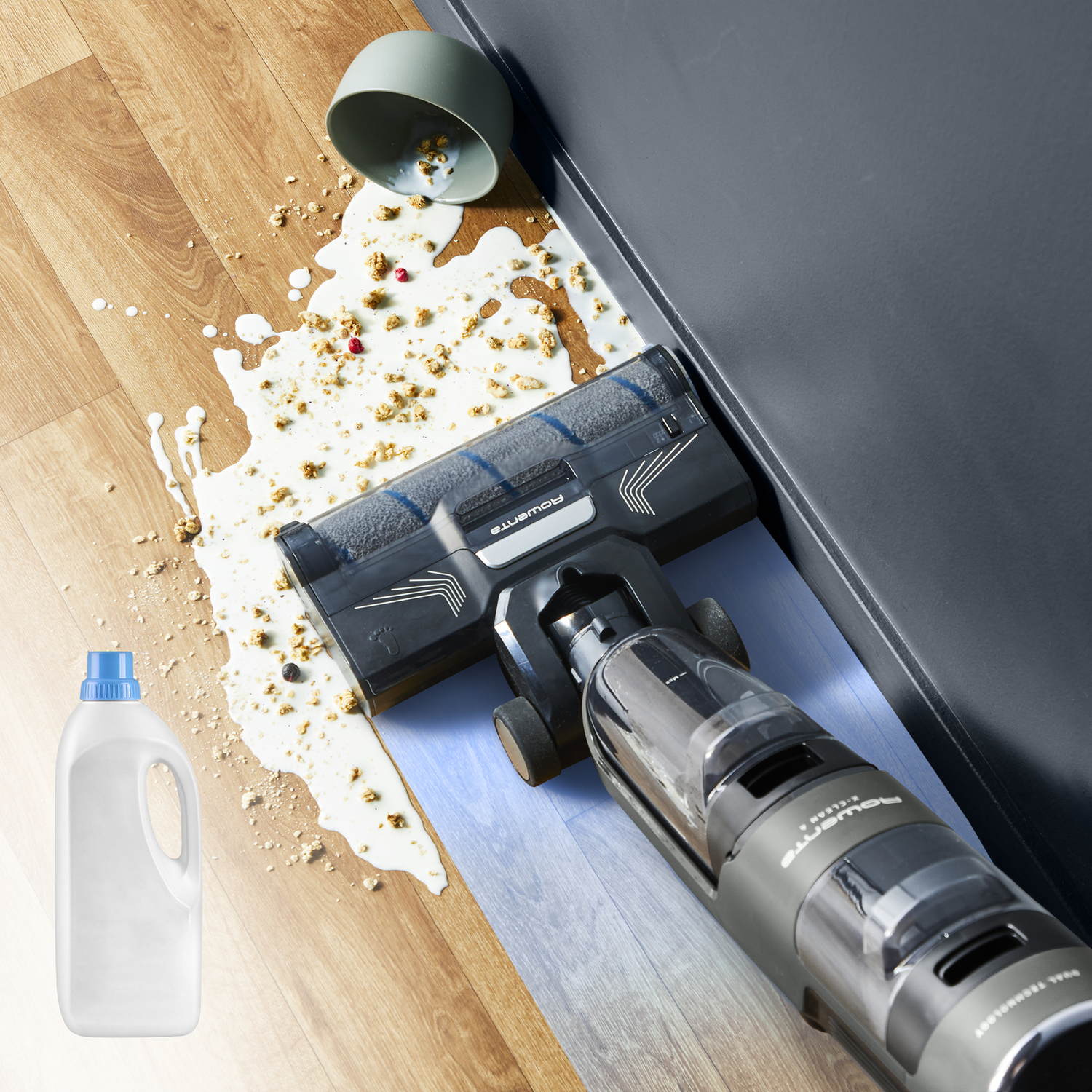 A vacuum cleaner is cleaning a floor where milk and food are spilled.