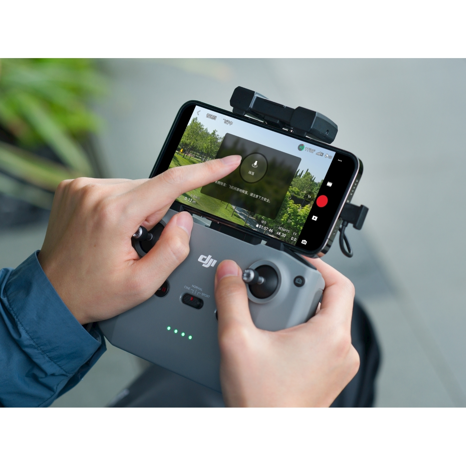 Una persona che tiene un controller per droni con un telefono collegato, che mostra un feed video in diretta.