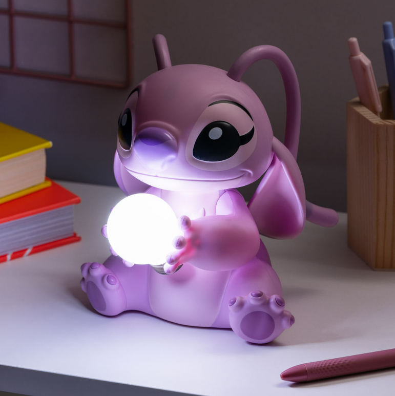 Rosa Cartoonfigur hält eine leuchtende Kugel. Auf einem Schreibtisch mit Büchern und Stiften sitzend.