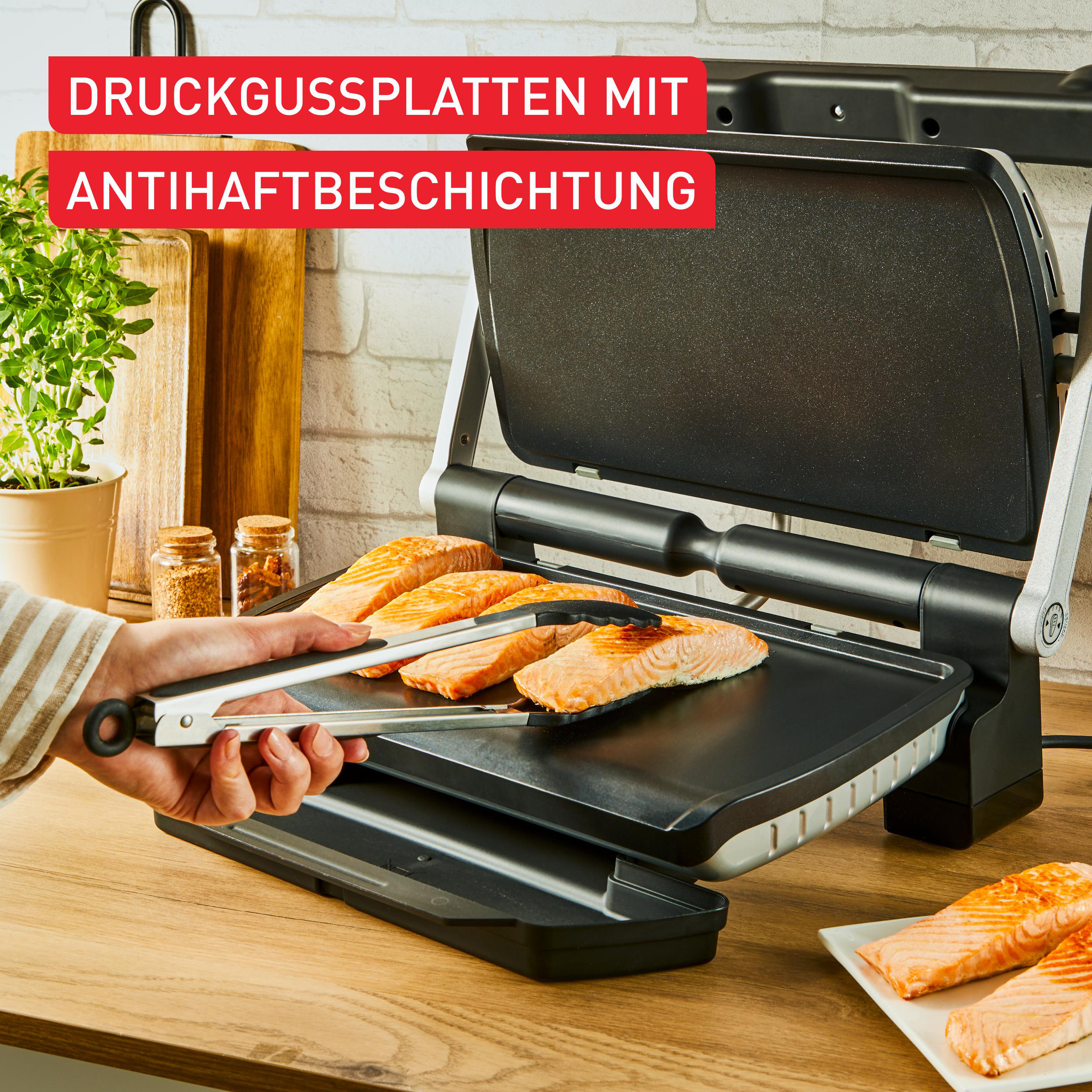 Grill mit Lachsschnitzel, die mit einer Zange auf eine Holzoberfläche gelegt werden.