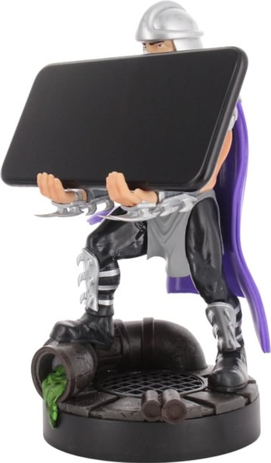 Shredder-Figur hält Tablet, steht über Kanalgitter mit grünem Schleim.