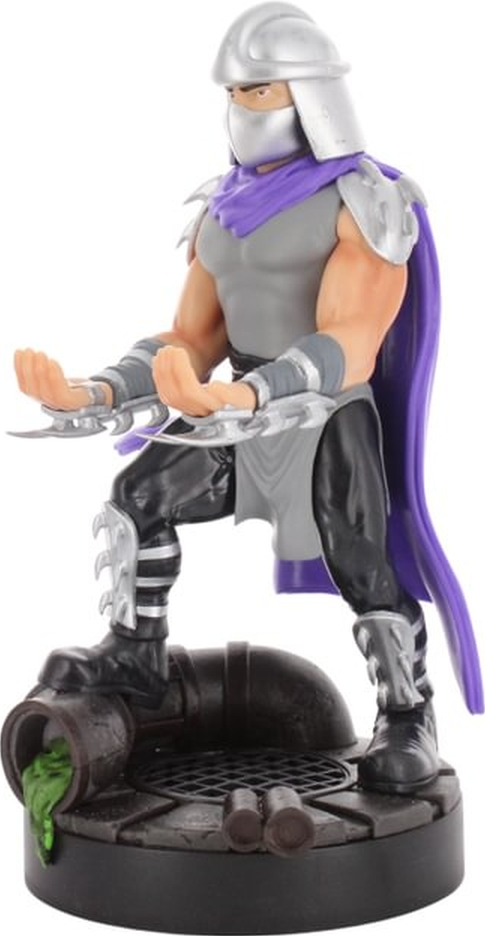 Shredder-Figur steht auf einem Kanaldeckel. Er trägt Rüstung, Umhang und hält Klingen.