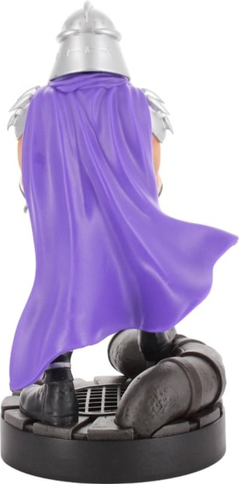Shredder-Figur mit lila Umhang auf einem Sockel. Silberner Helm und Schulterpolster. Schwarze Stiefel und Beine.