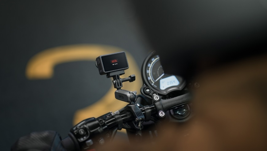Kamera sportowa zamontowana na kierownicy motocykla, pokazująca dane na ekranie.