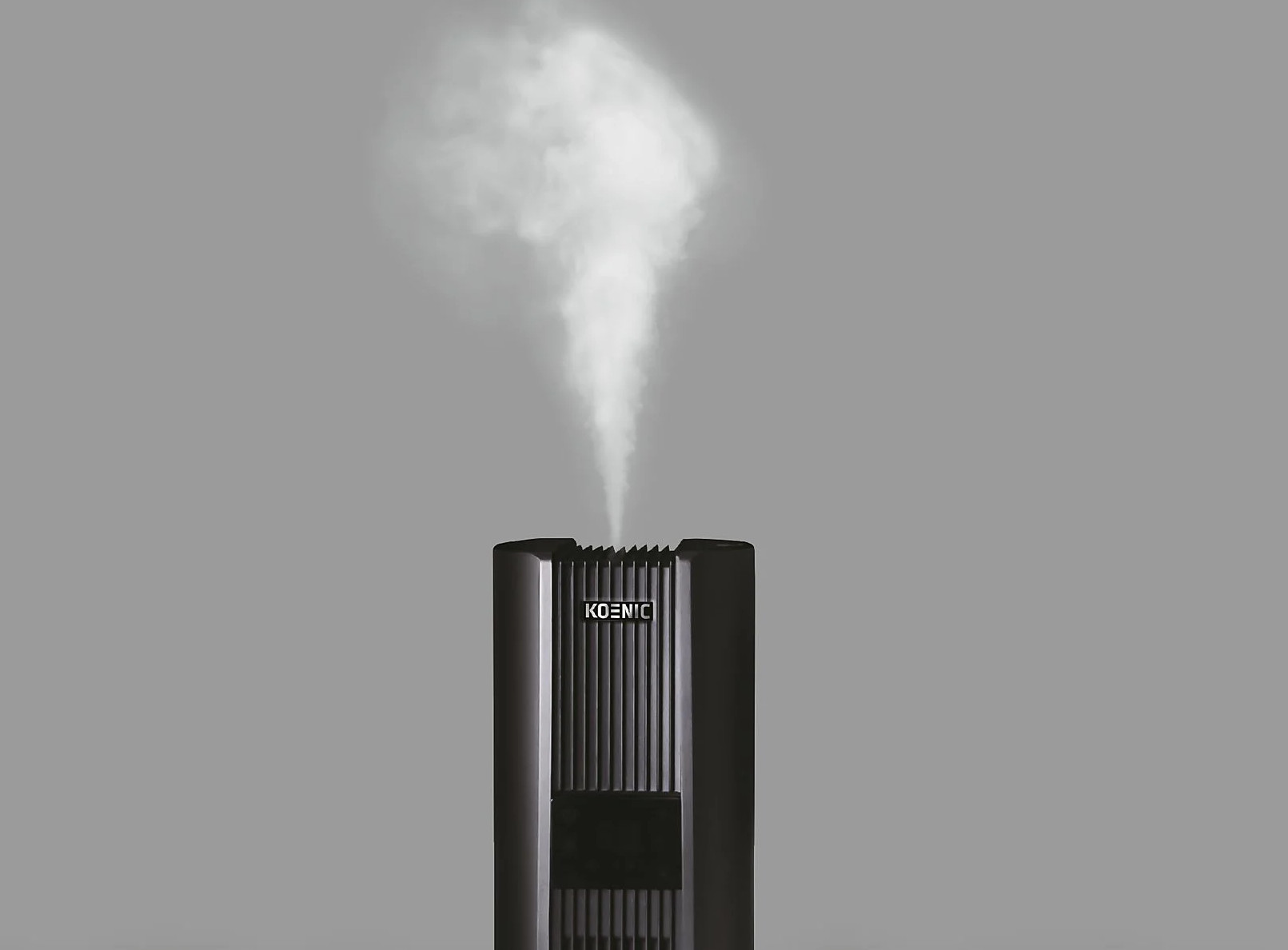 Czarny nawilżacz powietrza z wydobywającą się parą. Szare tło.