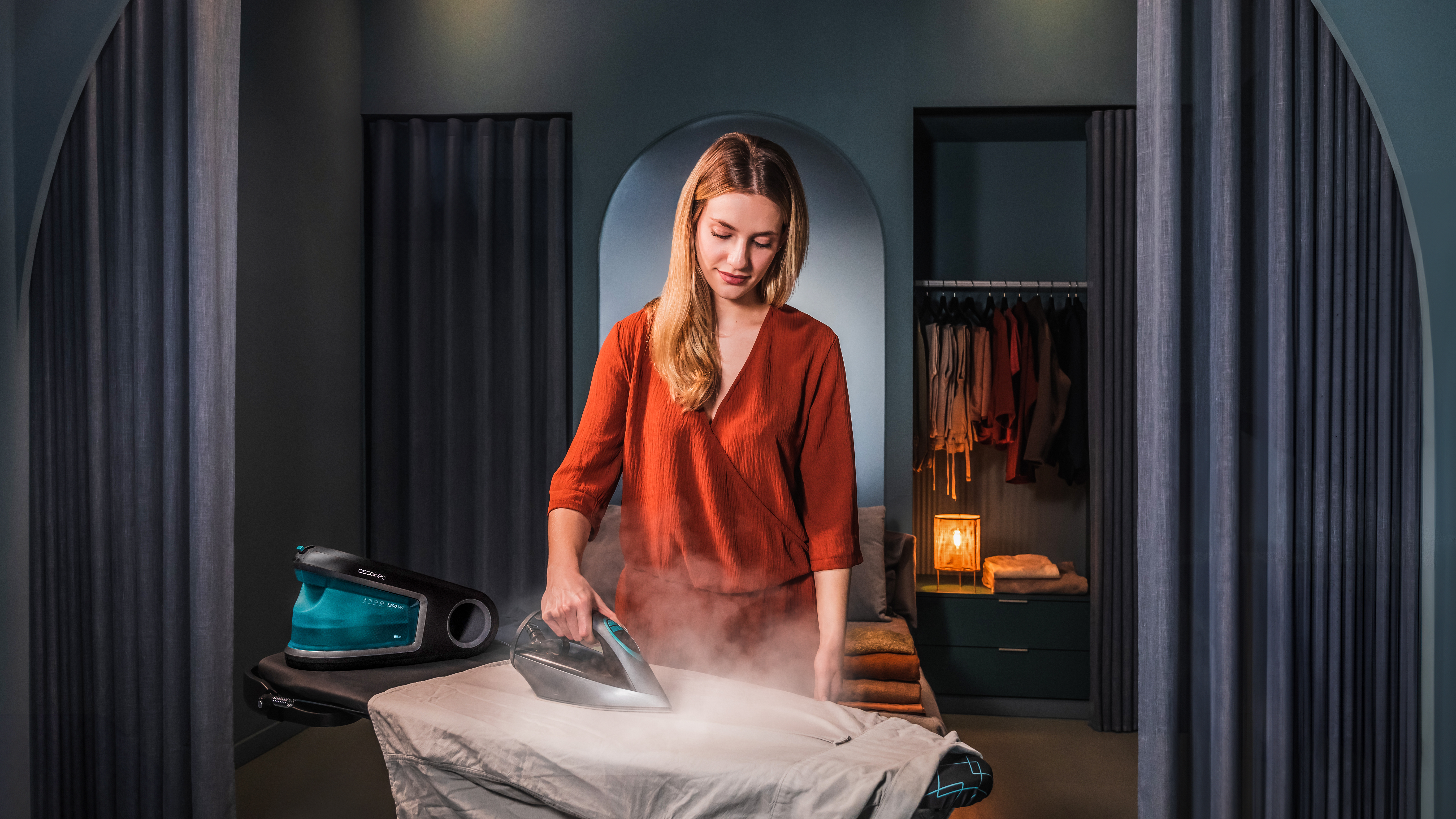 Mujer planchando una camisa, vapor subiendo, plancha, tabla de planchar y habitación.