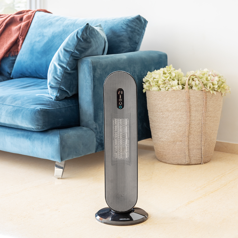 Un calentador eléctrico negro y plateado se encuentra frente a un sofá azul.