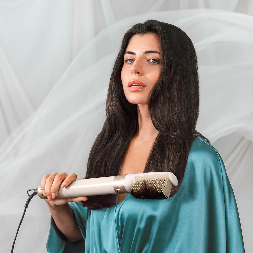 Una mujer con una bata azul sosteniendo un cepillo de peinado con cabello largo y oscuro.