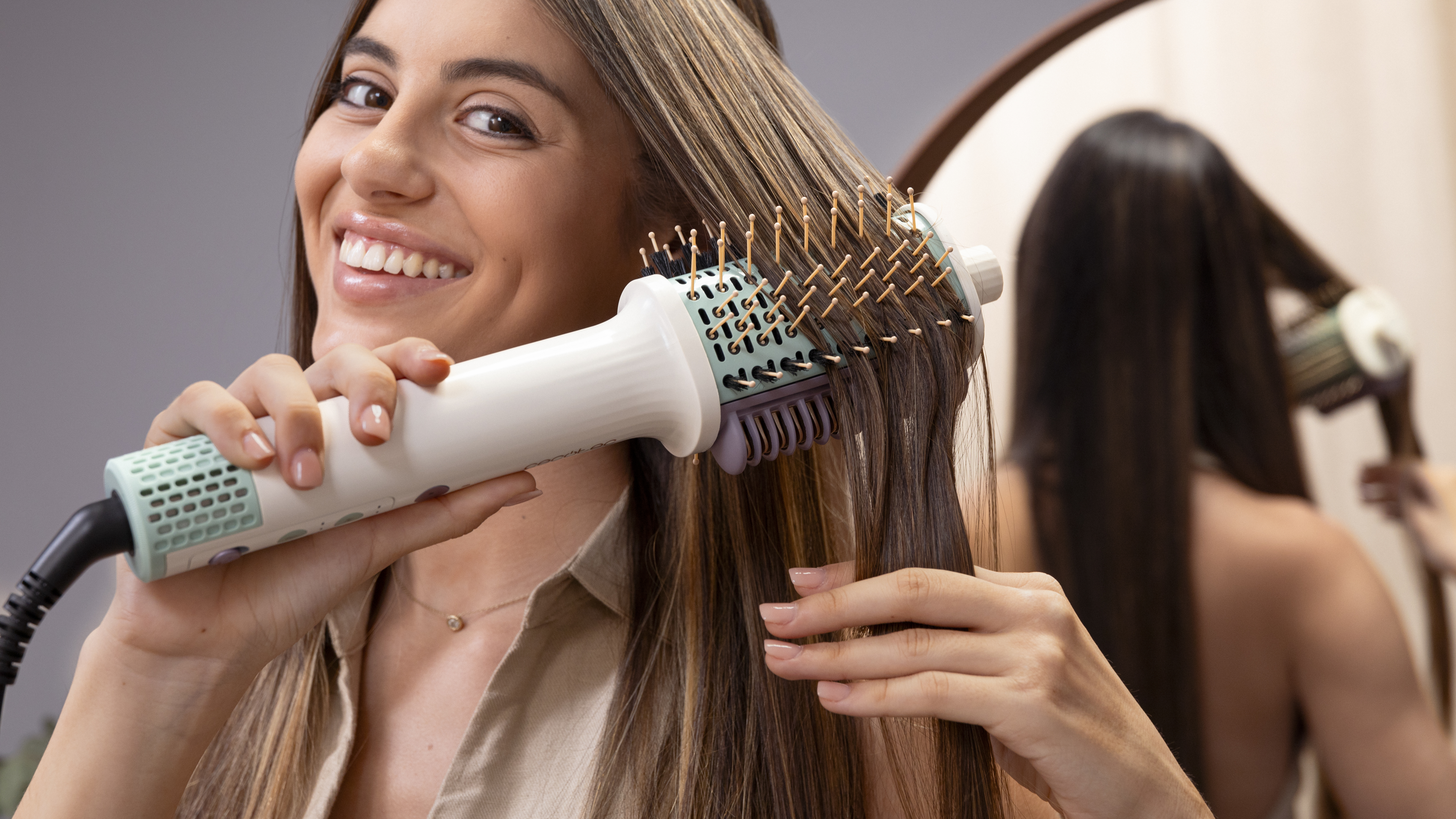 Mujer usando un cepillo para peinar el cabello frente a un espejo.