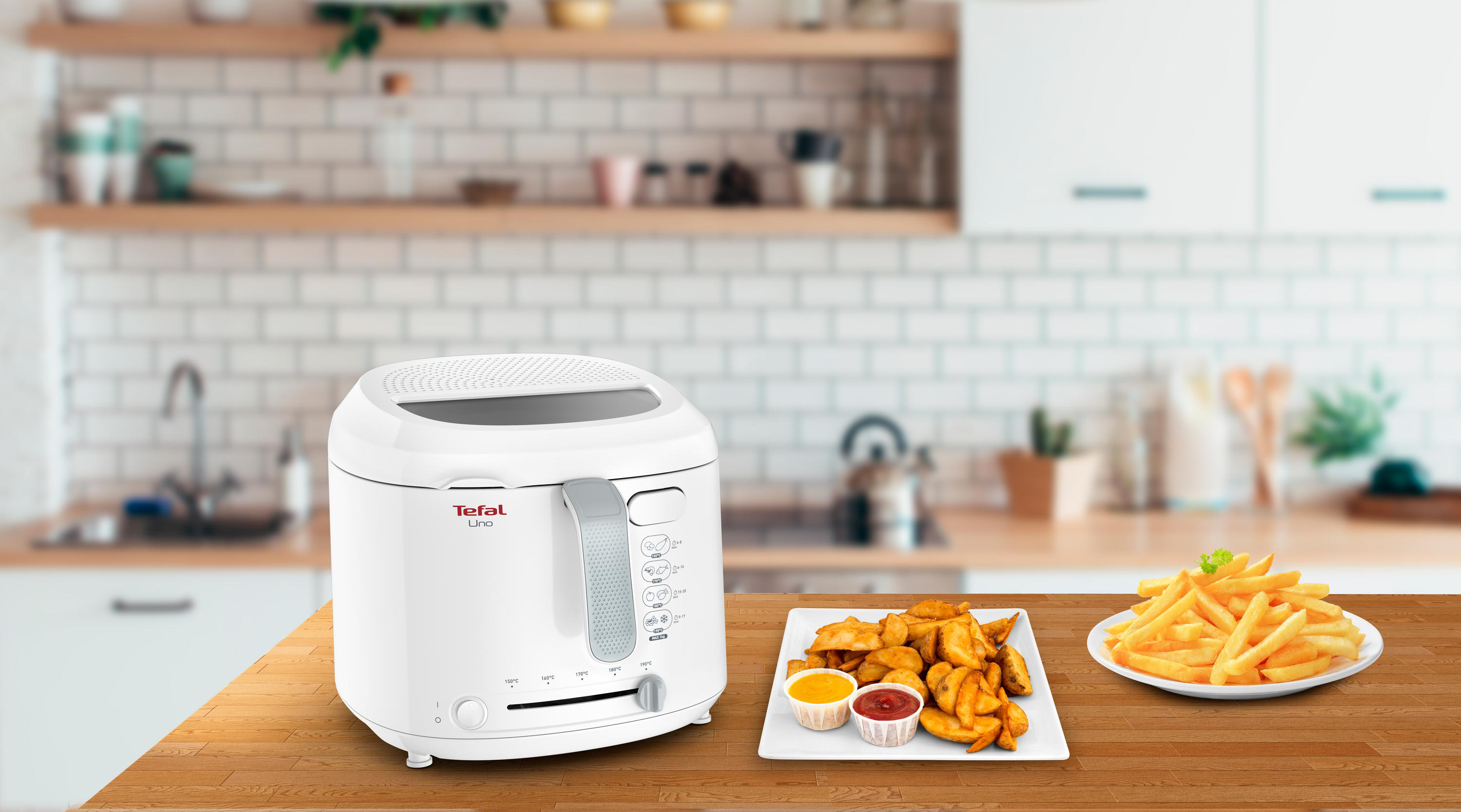 Weißer Tefal-Frittierer mit Speisen auf einem Holztisch.