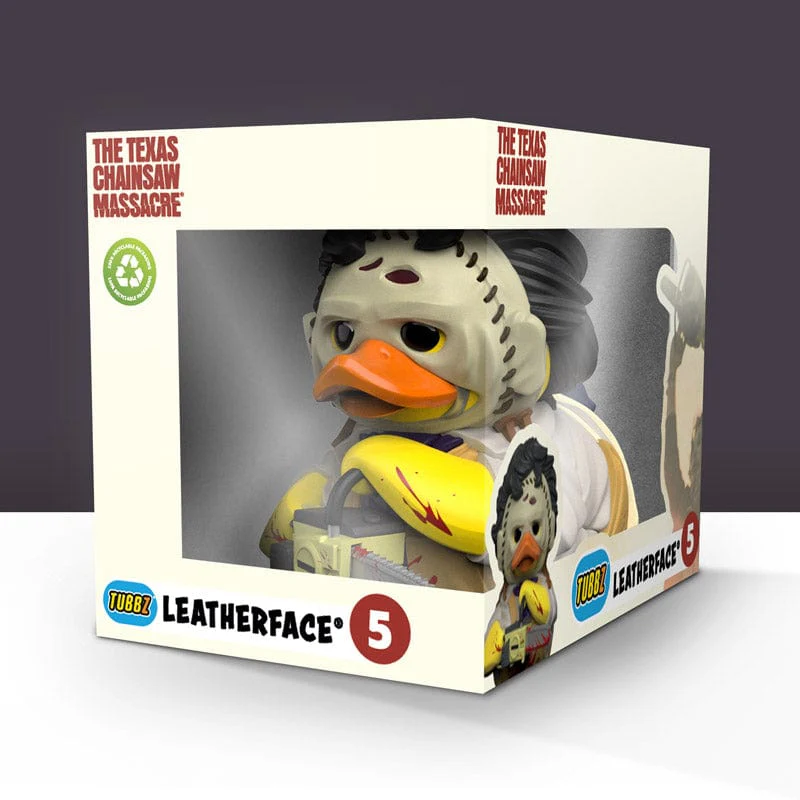 Egy Leatherface TUBBZ kacsafigura egy bemutató dobozban, sötét háttér előtt.