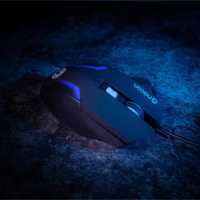 Fekete gamer egér kék fényekkel egy kék tónusú felületen. Az egéren Nacon logó látható.