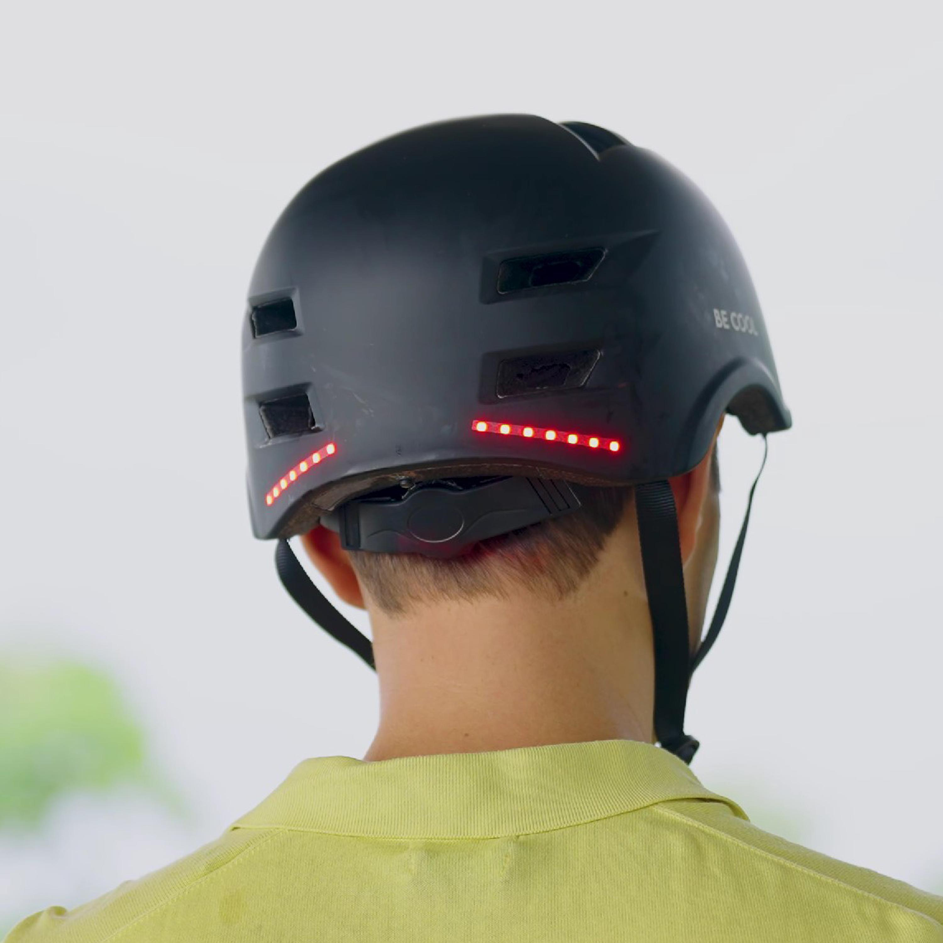 Schwarzer Fahrradhelm mit roten Lichtern hinten und einem gelben Hemd.