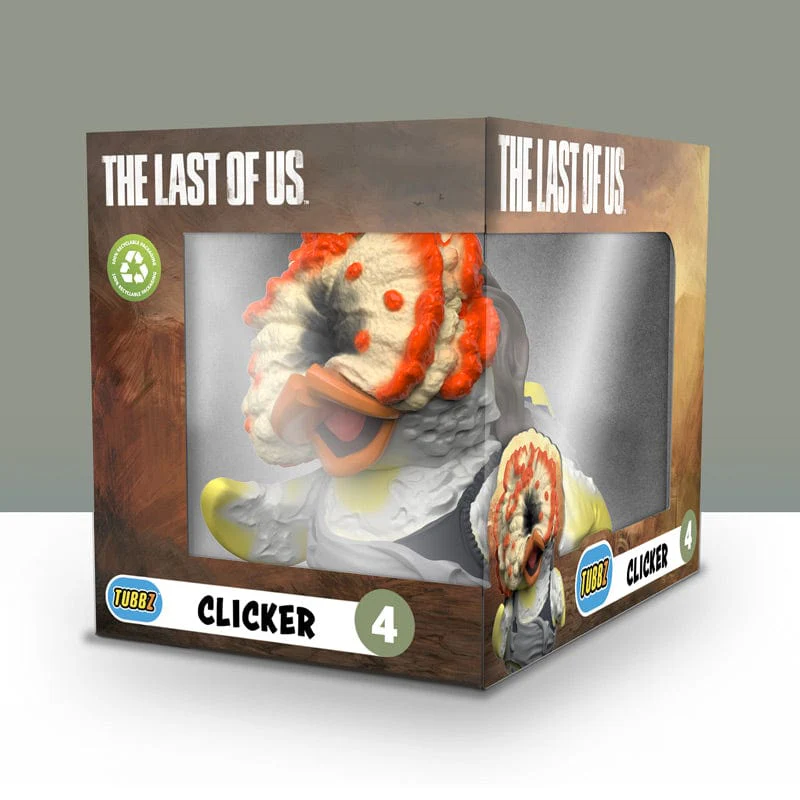 Egy 'Clicker' kacsa játék a 'The Last of Us'-ból egy dobozban. A játék fehér és narancssárga, a dobozon szöveg látható.