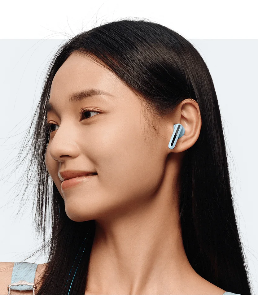 Femme avec des écouteurs sans fil bleus dans les oreilles, souriante et regardant de côté.
