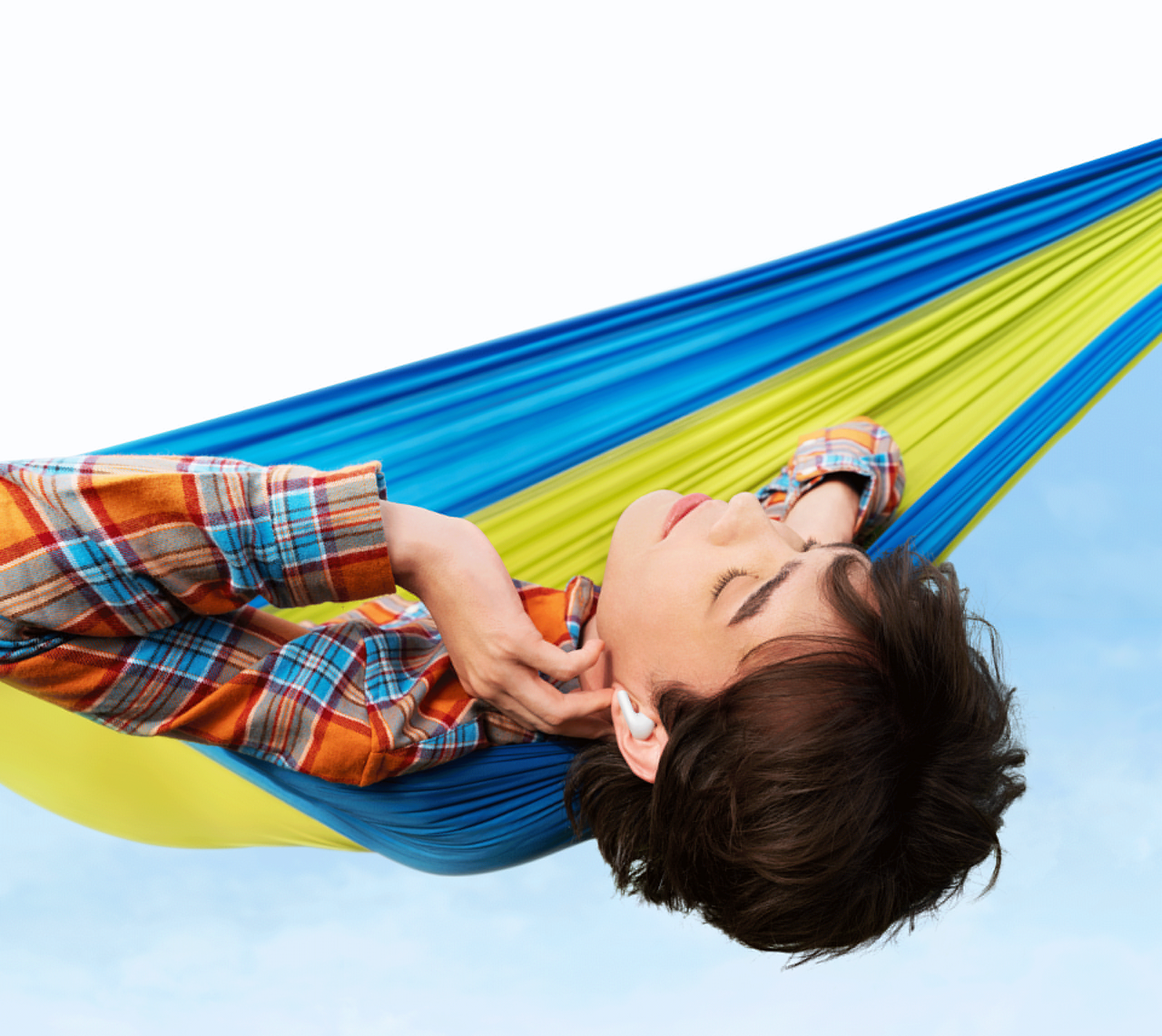 Jeune personne dans un hamac portant des écouteurs, se relaxant.