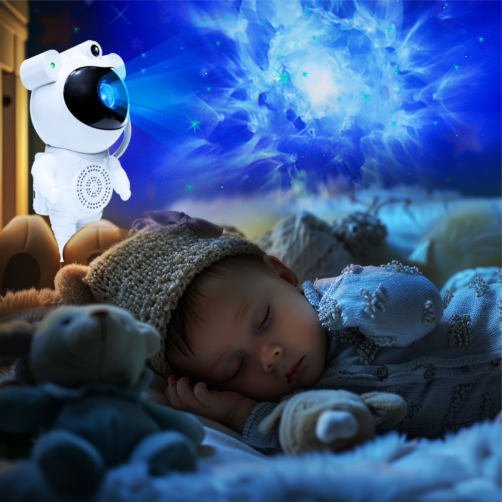 Dziecko śpi w łóżku z projektorem gwiaździstego nieba i pluszowymi misiami.