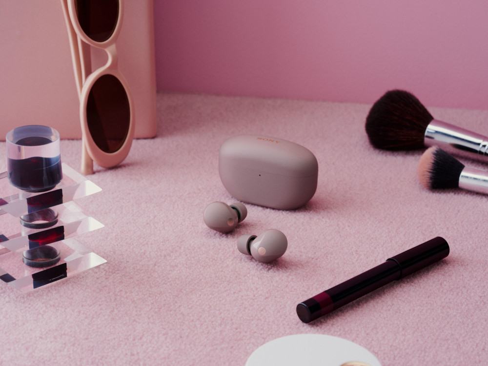 Écouteurs, étui, lunettes de soleil et maquillage sur une surface rose. Fond rose.