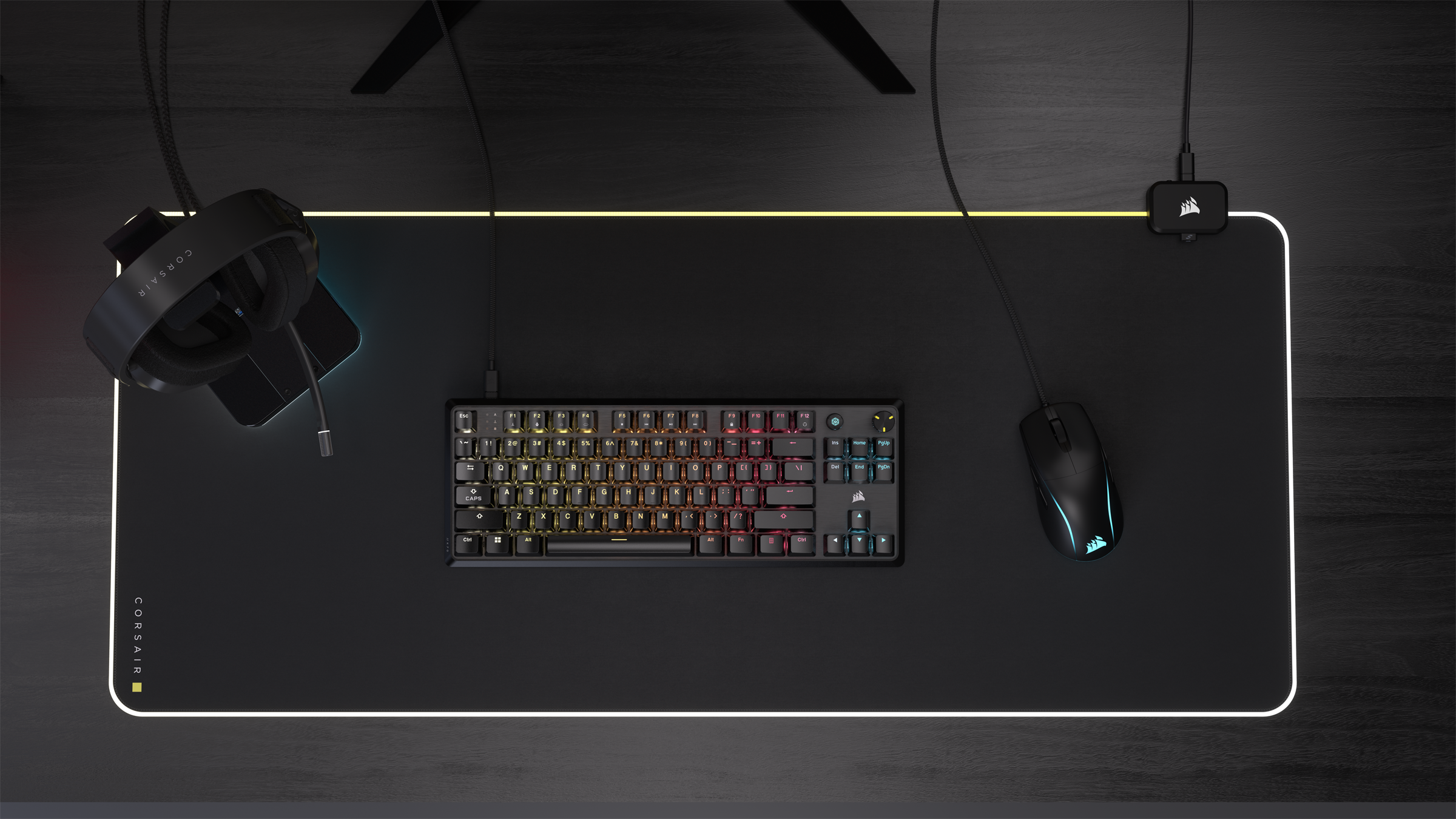 Configurazione scrivania con tastiera, mouse, cuffie. Mousepad nero con bordo bianco. Sfondo nero.
