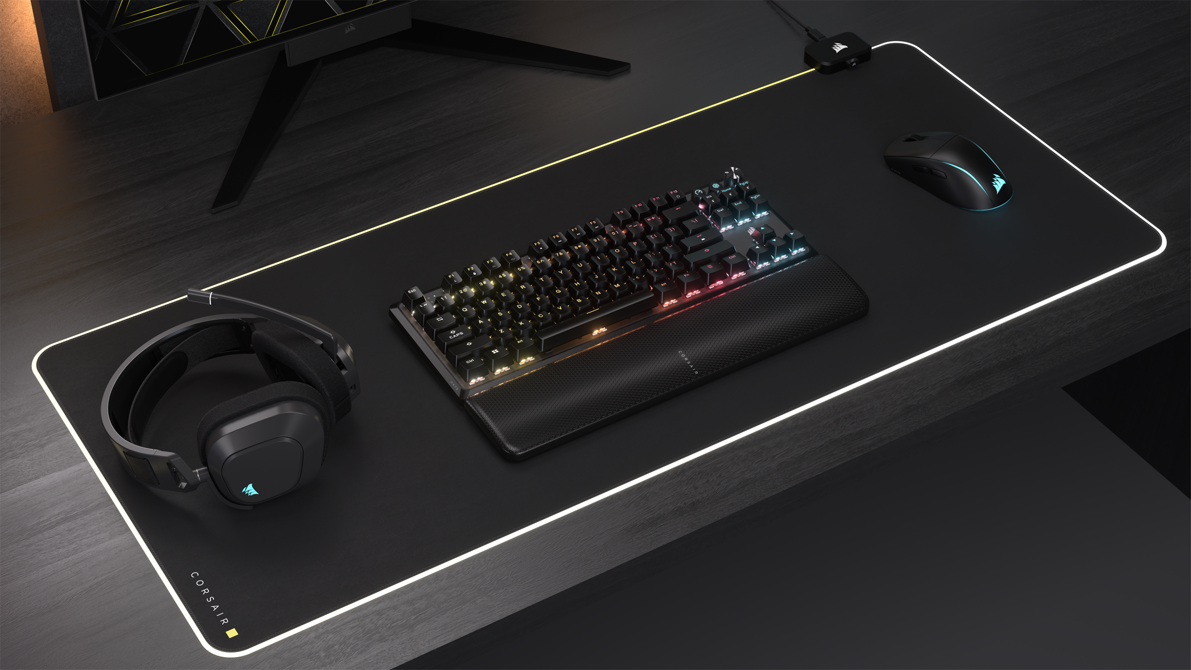 Configuration gaming: clavier, souris, casque et tapis de souris sur un bureau noir.