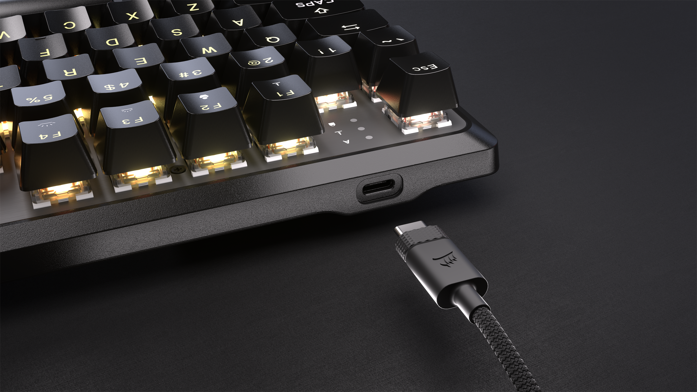 Una tastiera nera con tasti illuminati. Un cavo USB-C è collegato. La tastiera è su una superficie scura.