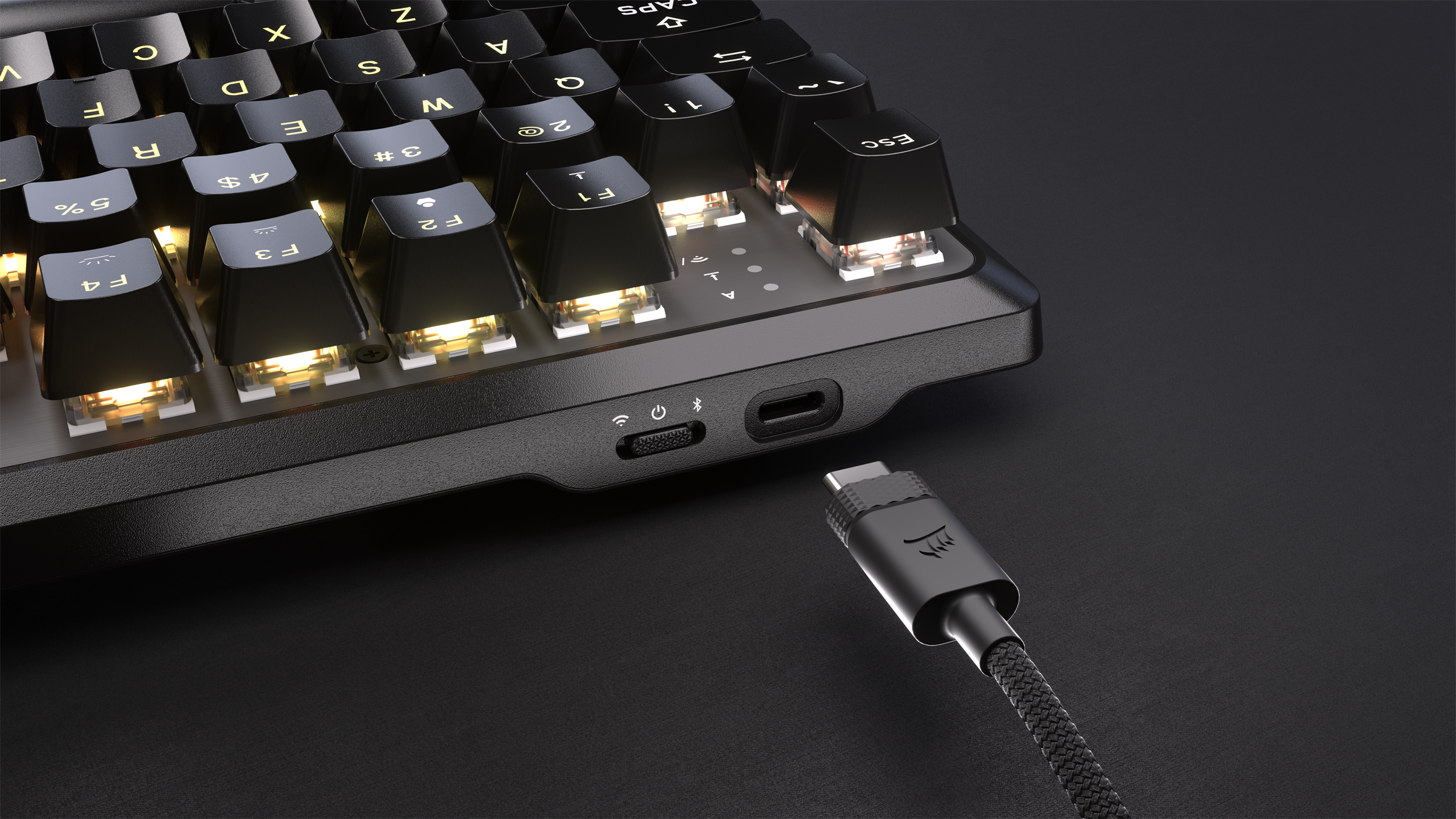 Gros plan sur un clavier noir avec un câble USB-C branché. Le fond est noir.