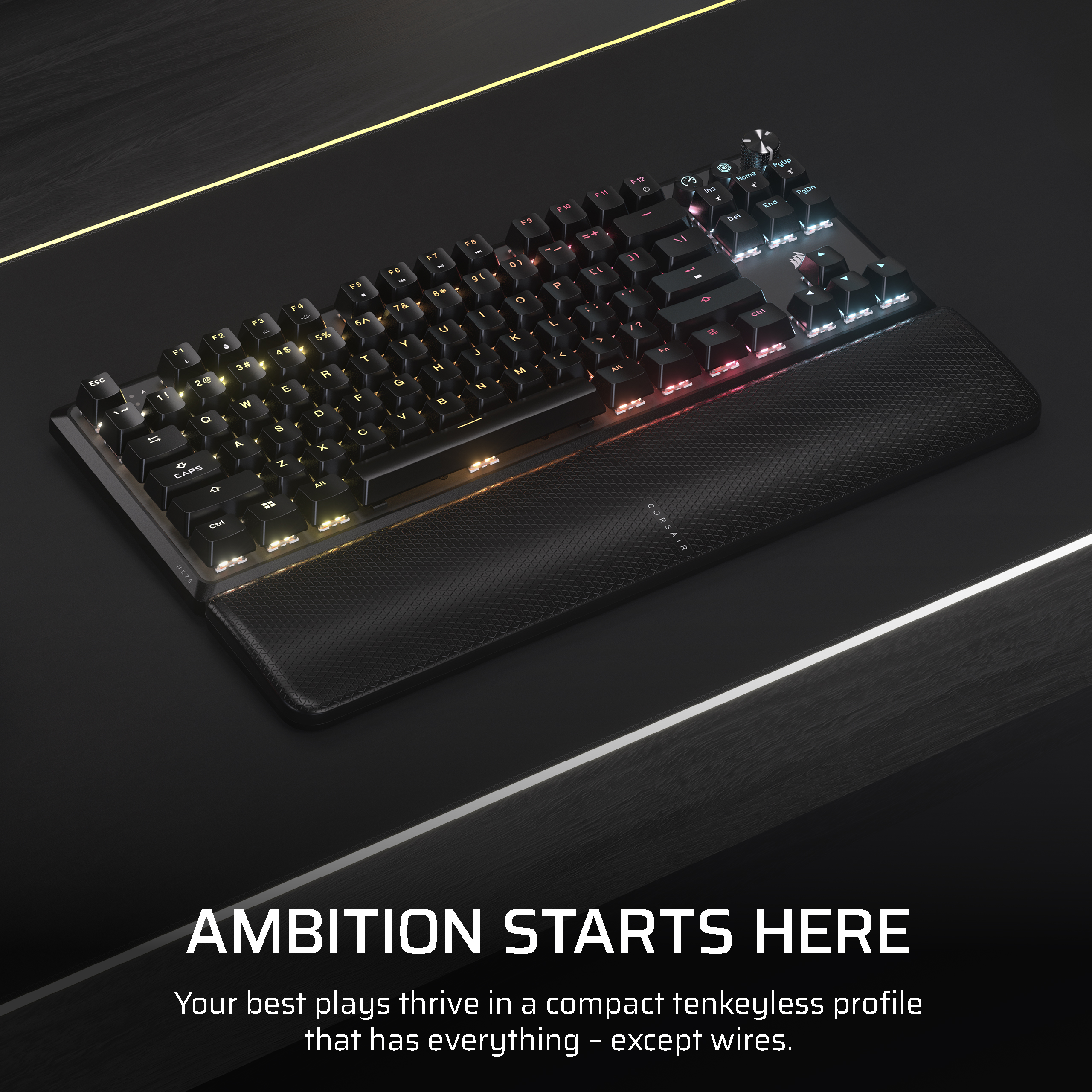Clavier noir avec touches colorées, repose-poignets et fond de bureau noir.