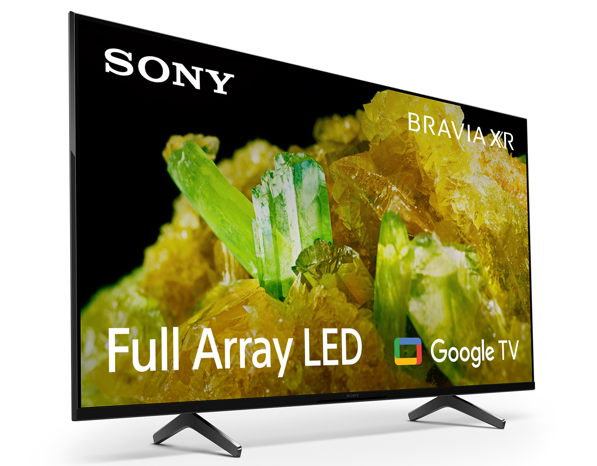 Telewizor Sony Bravia wyświetla kolorowe kryształy na czarnym tle. Telewizor stoi na białej powierzchni.