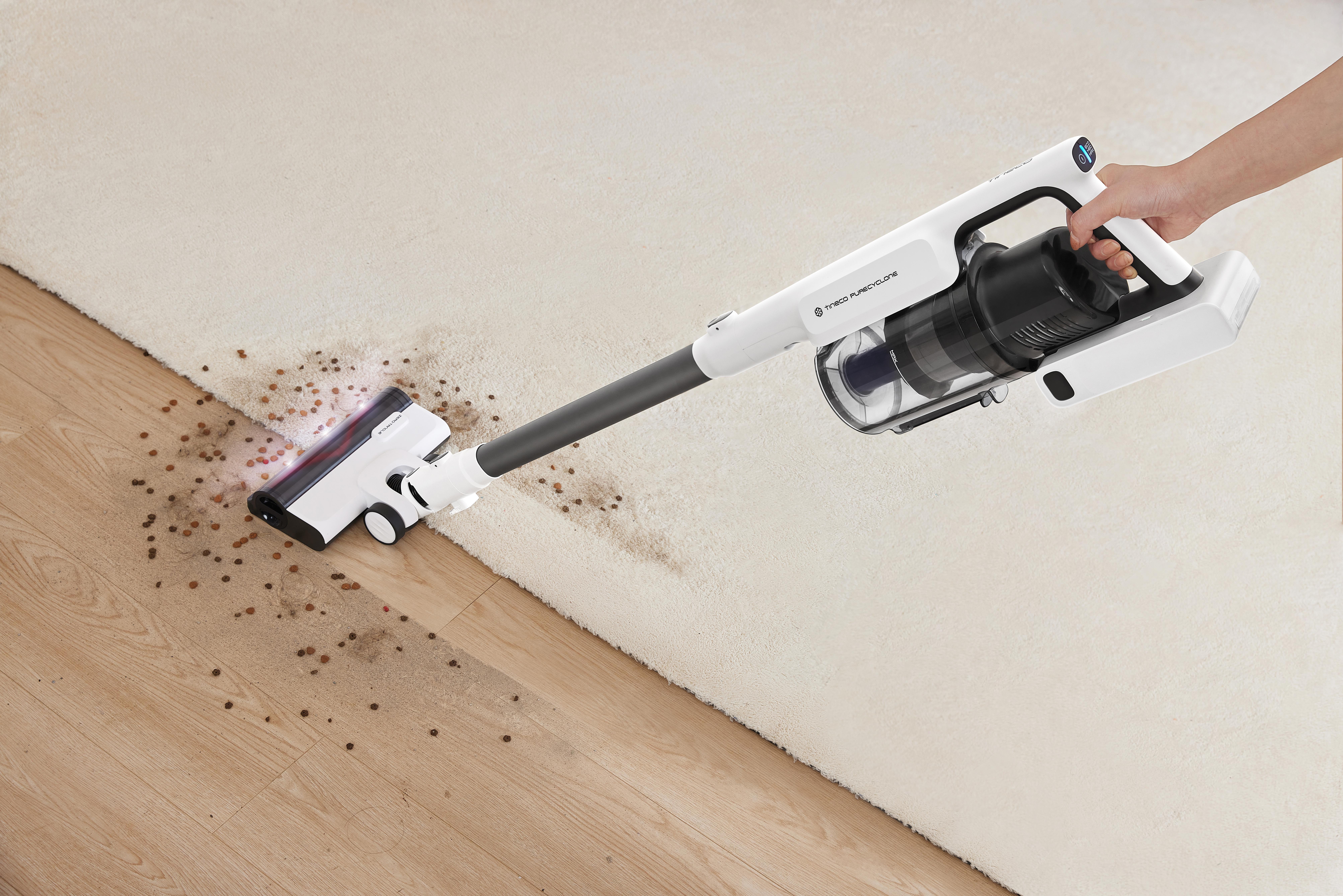 Person benutzt kabellosen Staubsauger auf Teppich.