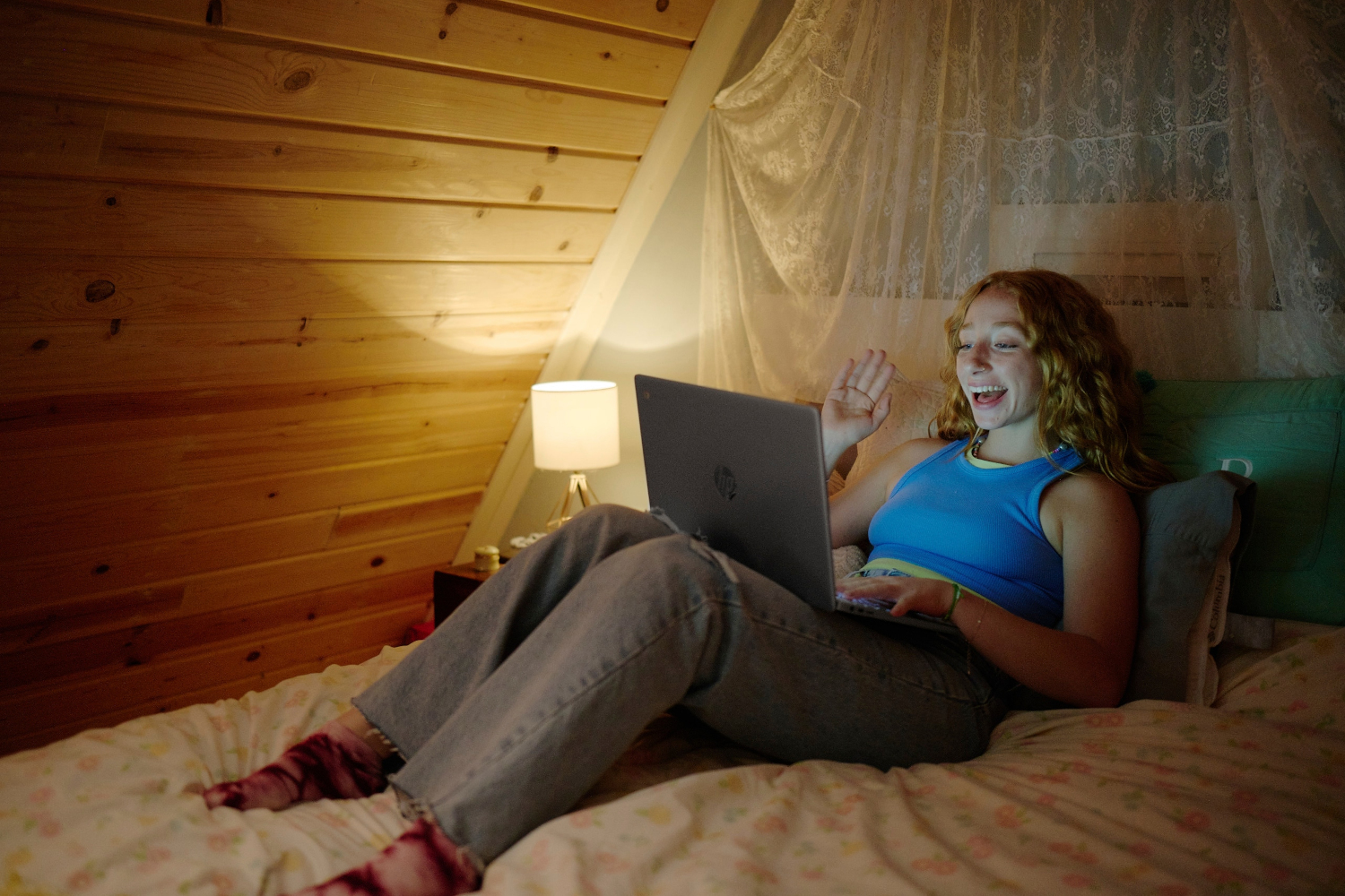 Vrouw die videochat op een laptop in een hutachtige omgeving.