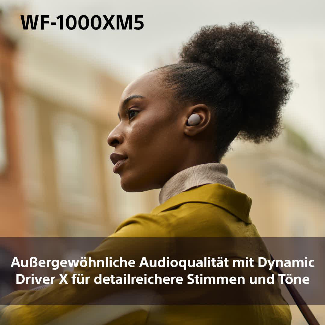 Eine Frau mit gelber Jacke und Ohrhörern. Der Hintergrund ist verschwommen.