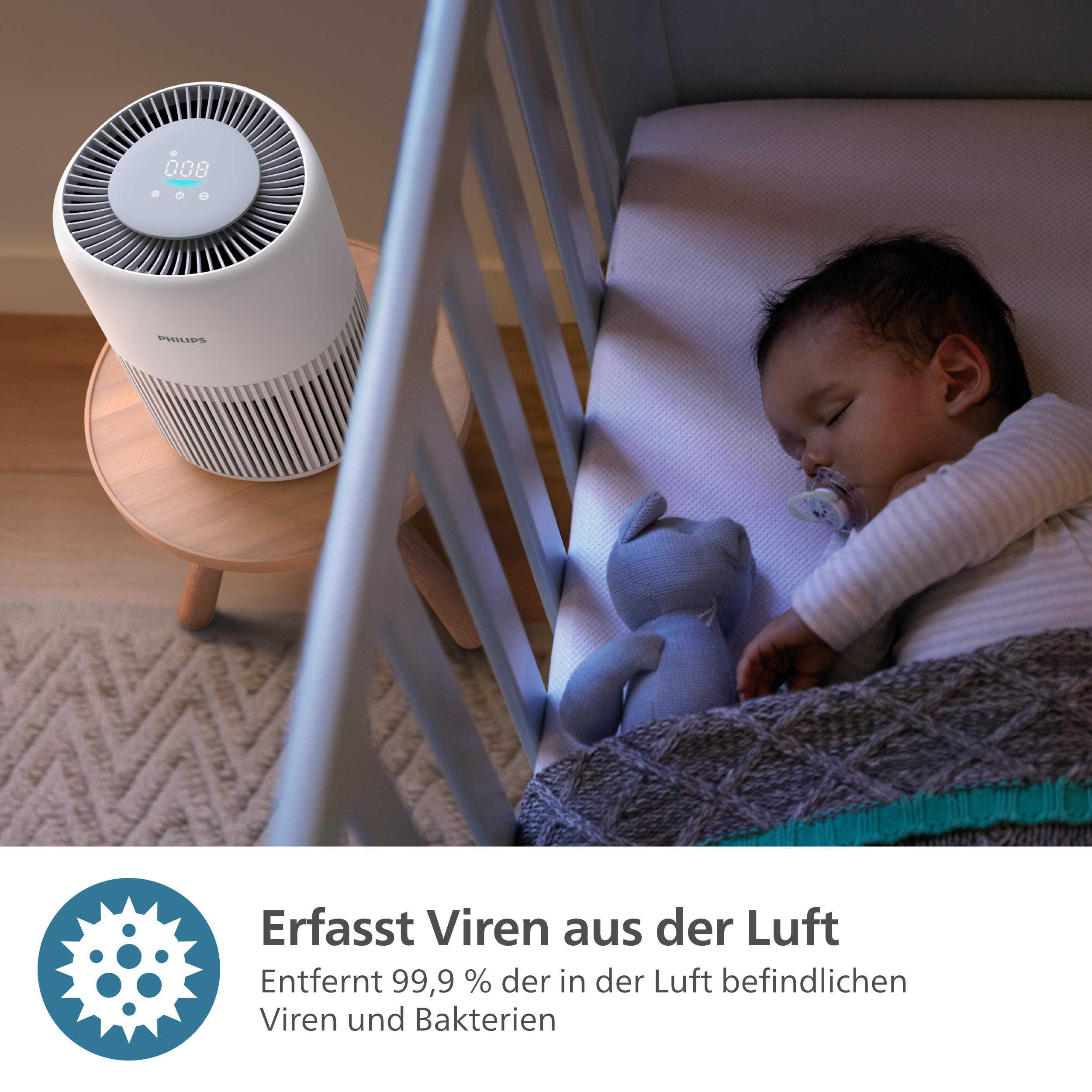 Ein Baby schläft in einem Kinderbett mit einem Luftreiniger in der Nähe. Text besagt, dass es Viren entfernt.