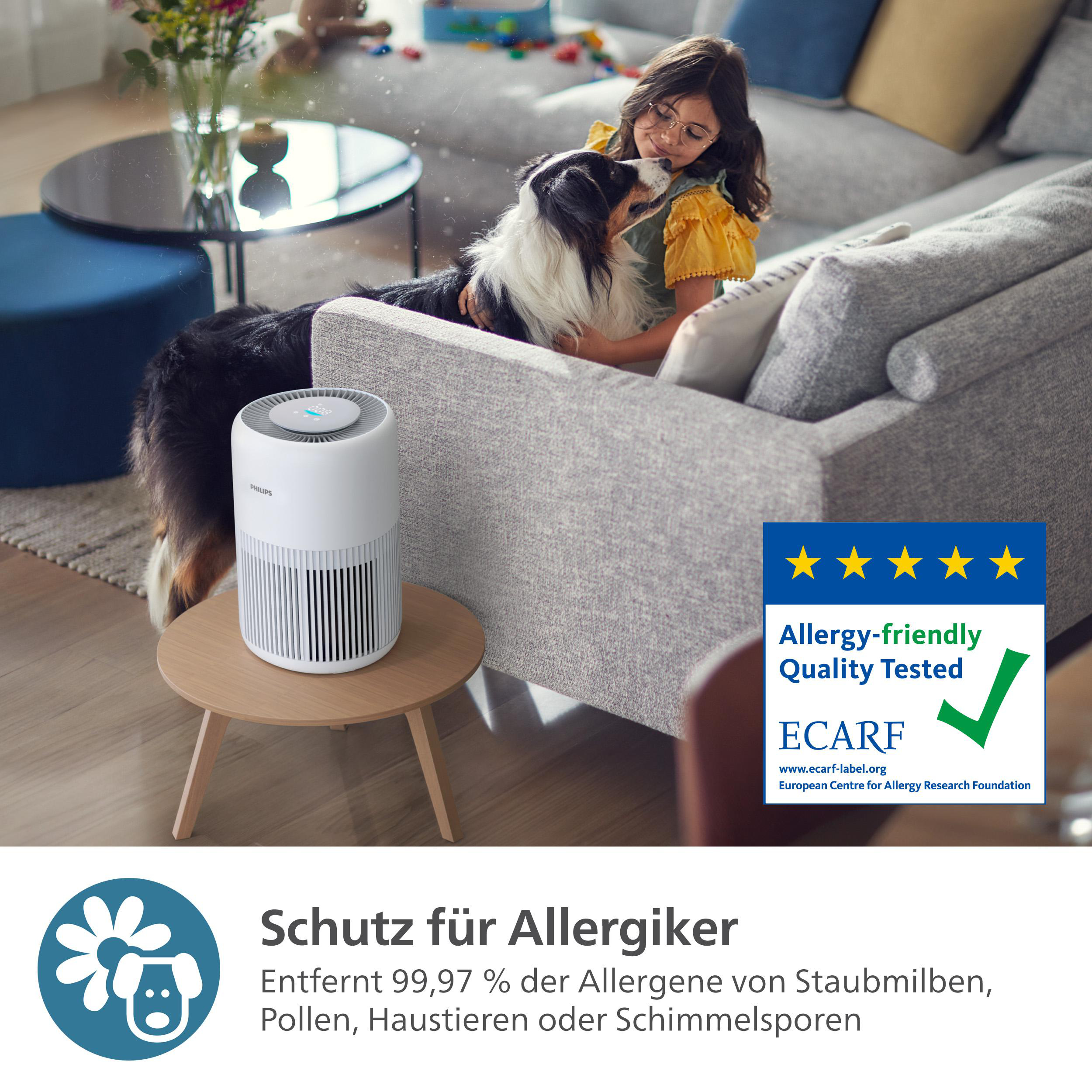 Mädchen mit Hund auf grauem Sofa, Luftreiniger auf Tisch und allergiefreundliches Abzeichen.