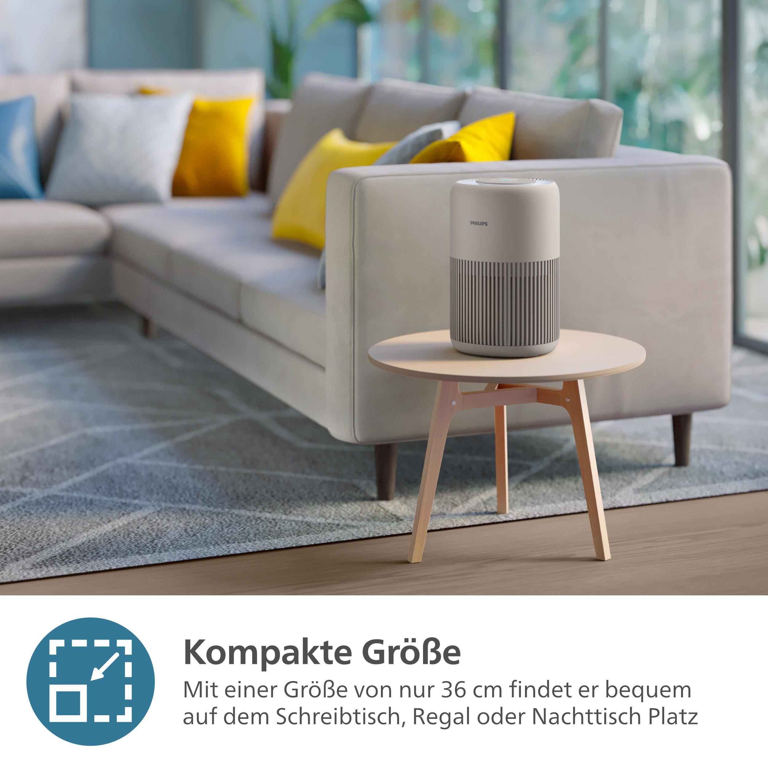 Ein Luftreiniger auf einem kleinen Tisch im Wohnzimmer. Ein Sofa und ein Teppich sind sichtbar.
