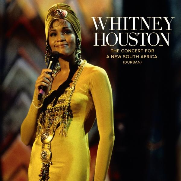Whitney Houston auf der Bühne mit Mikrofon, gelbes Kleid und Turban. Konzert für Südafrika.