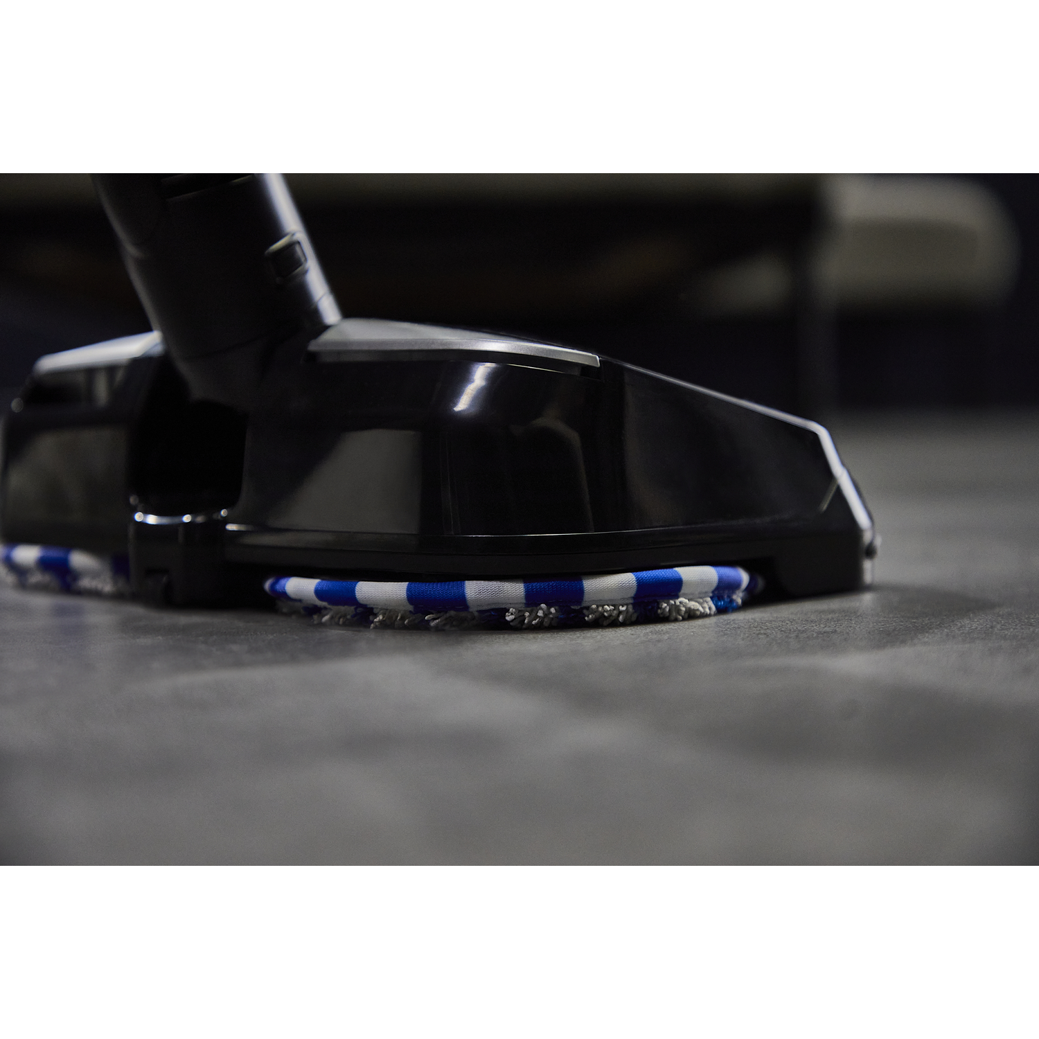 Close-up of a vacuum cleaner head on a gray floor.