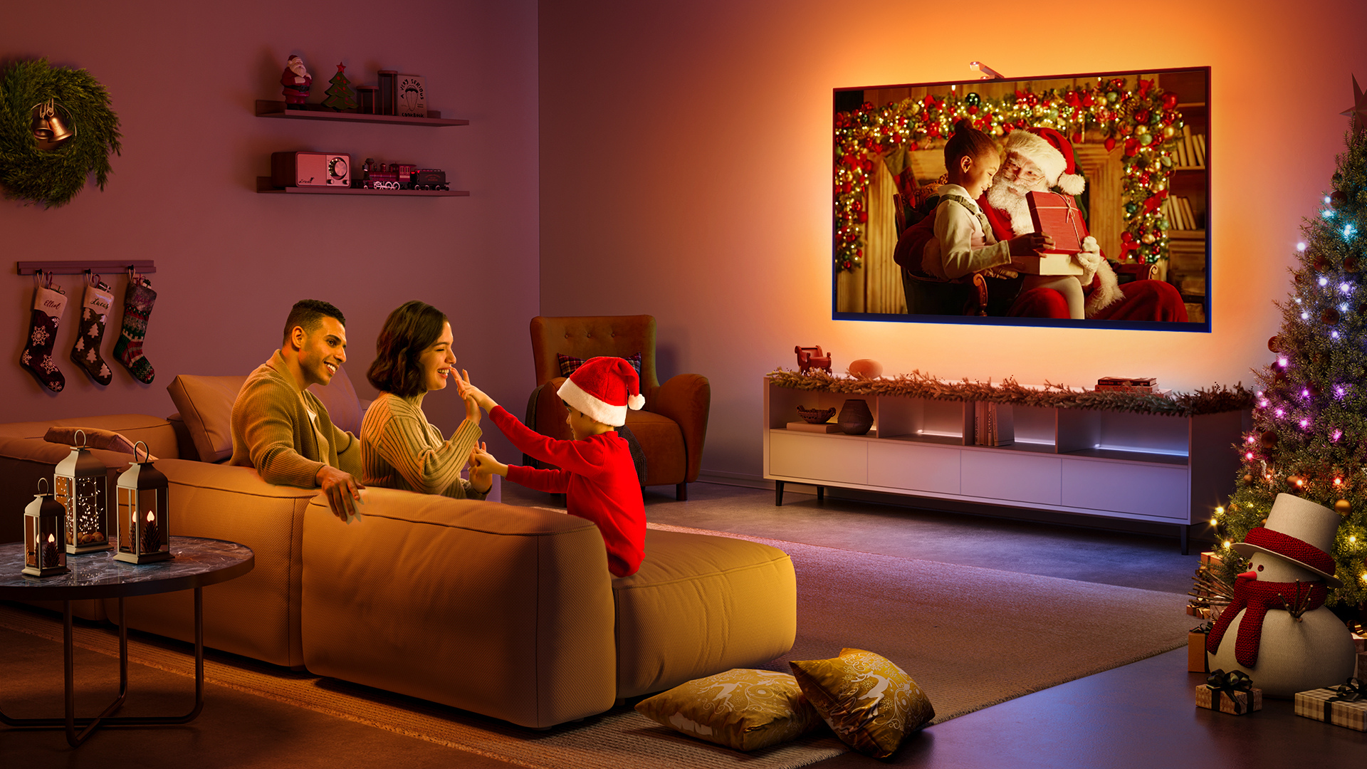 Renkli ışıklar ve süslemelerle bir TV'de Noel temalı bir film izleyen bir aile.