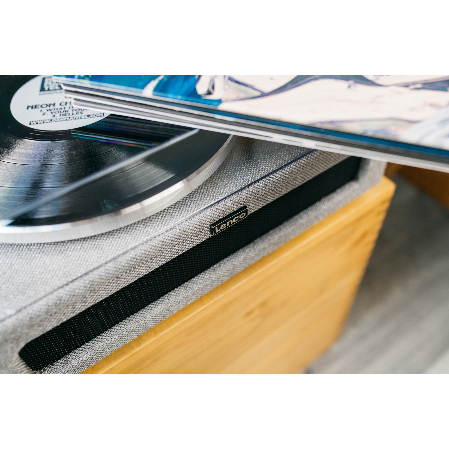 Turntable with a record, and a stack of vinyl records in the background.