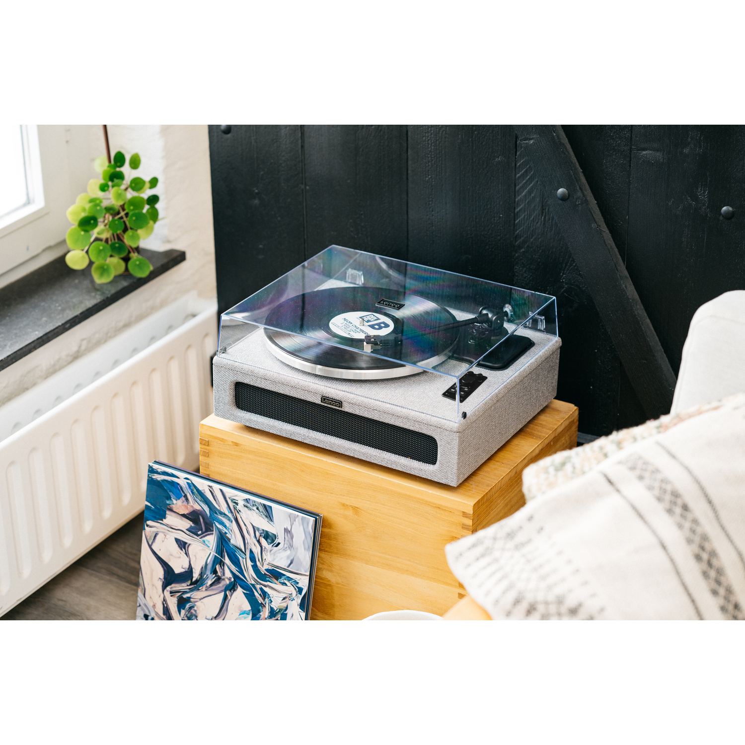 A turntable playing a vinyl record, with a clear cover and other items on a wooden surface.
