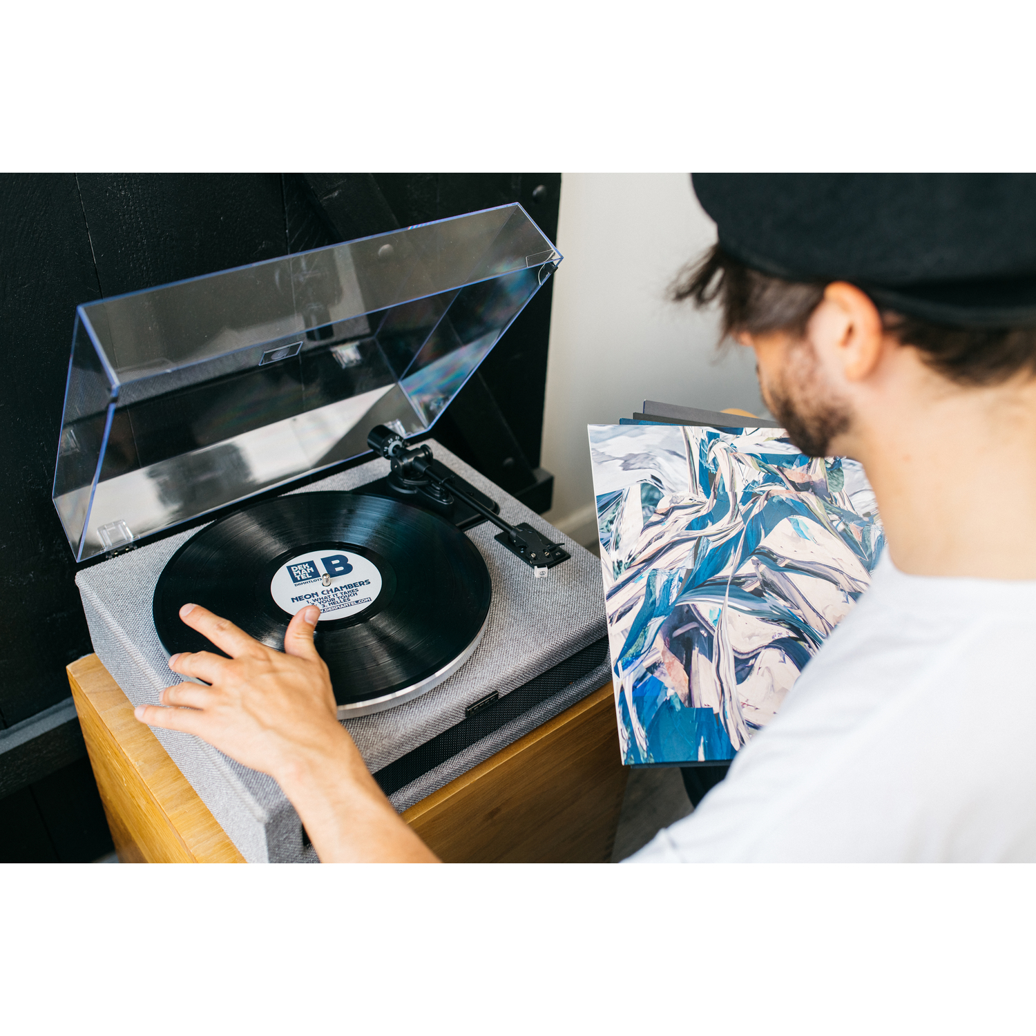 Man with beard holding a vinyl record near a record player.