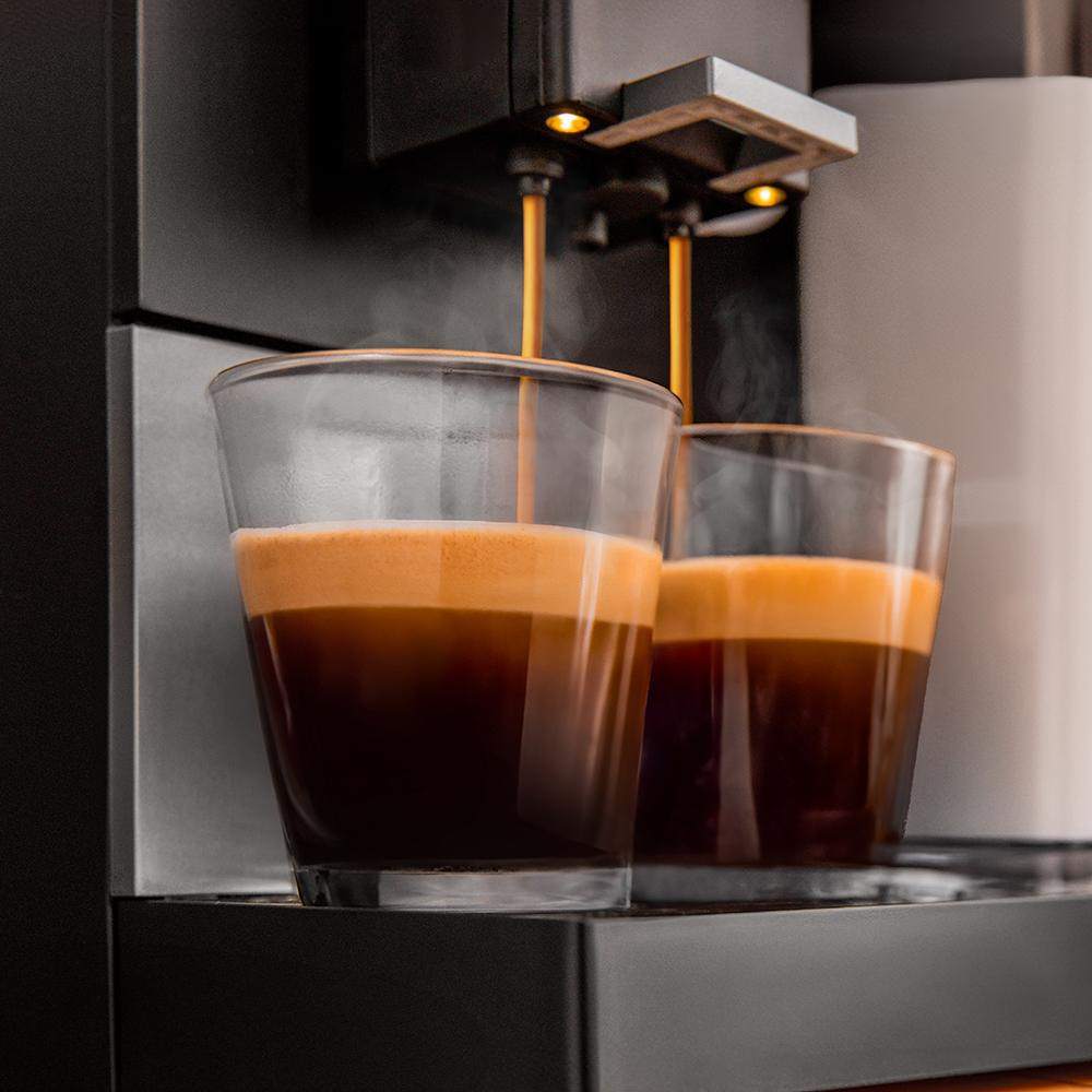 Dos vasos de espresso con crema siendo dispensados ​​de una máquina de café.